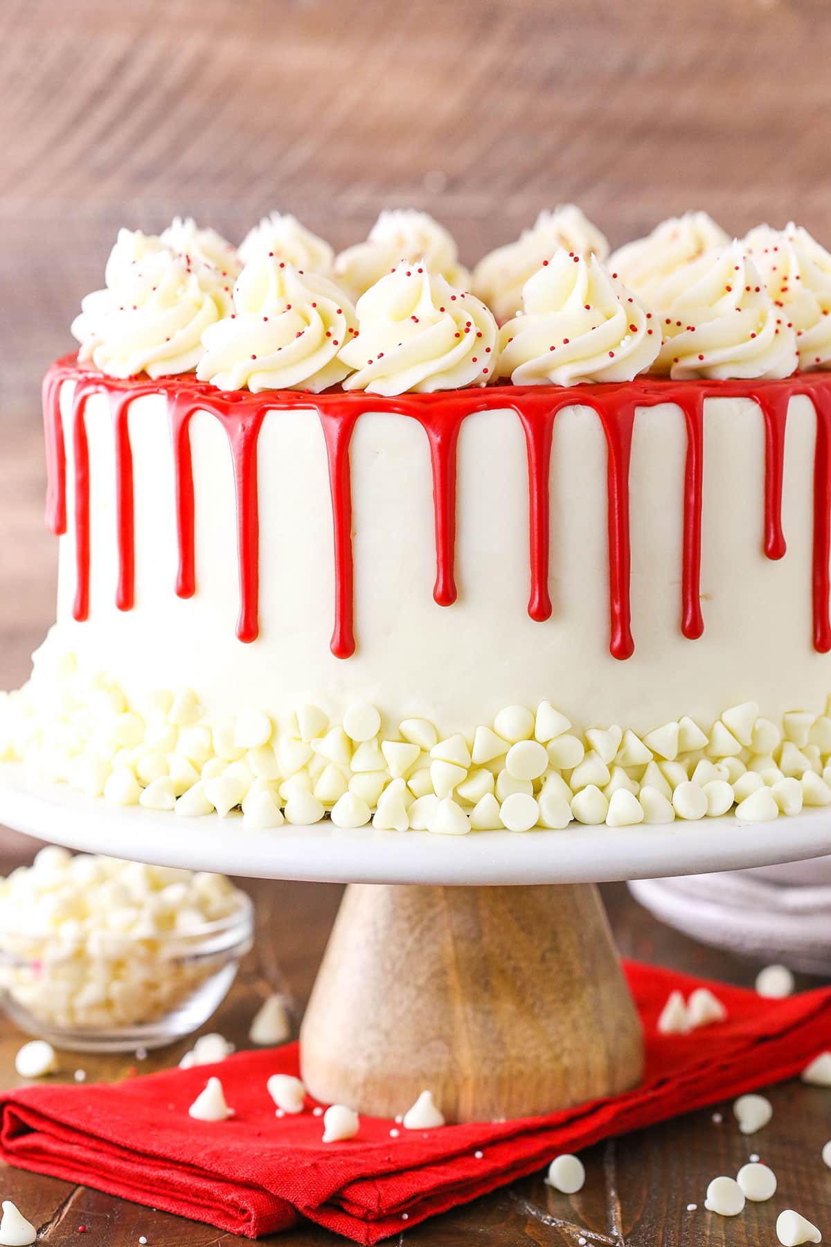Side view of a full Red Velvet Cheesecake Cake on a wooden cake stand