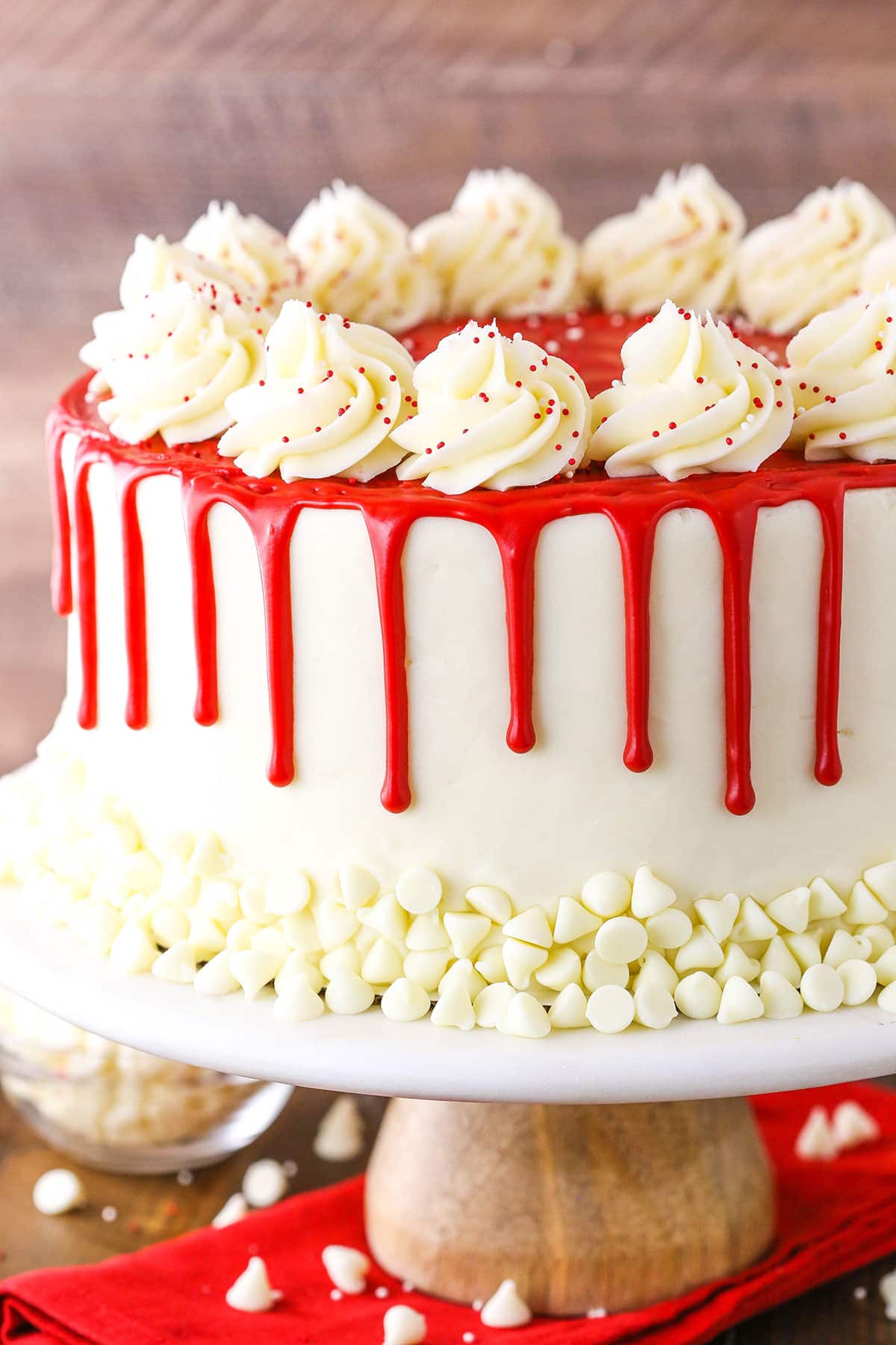 Side view of a full Red Velvet Cheesecake Cake on a wooden cake stand