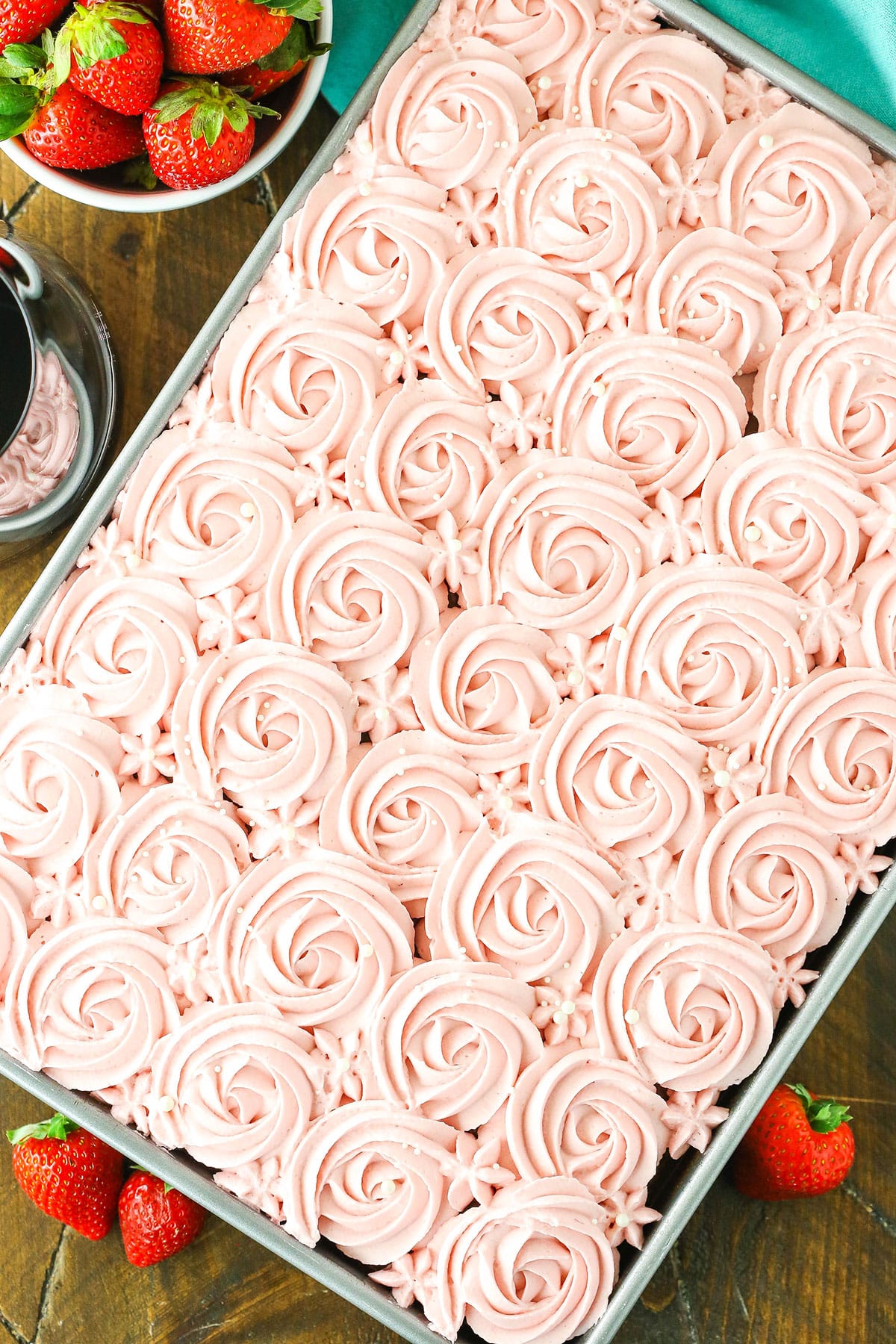 Overhead view of a full Red Wine Chocolate Poke Cake in a metal cake pan with strawberries in the background