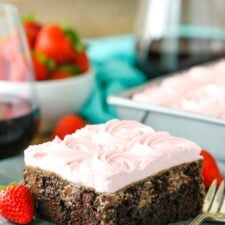 A square slice of Red Wine Chocolate Poke Cake next to a fork on a gray plate