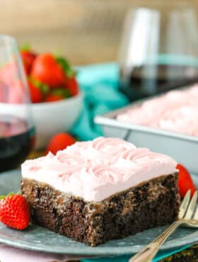 A square slice of Red Wine Chocolate Poke Cake next to a fork on a gray plate