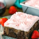 A square slice of Red Wine Chocolate Poke Cake with a bite removed next to a fork on a gray plate