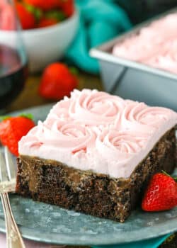 A square slice of Red Wine Chocolate Poke Cake with a bite removed next to a fork on a gray plate