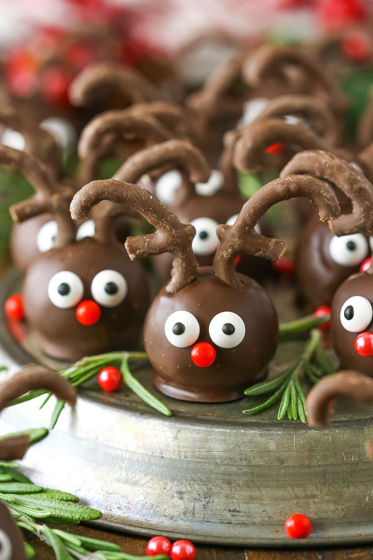 Side view of Reindeer Cookie Balls on a gray platter and surrounded by rosemary