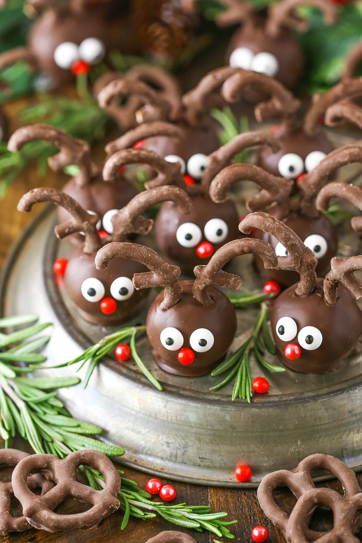 Side view of Reindeer Cookie Balls on a gray platter and surrounded by rosemary