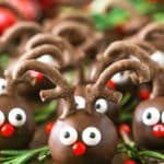 Side view of Reindeer Cookie Balls on a wooden table surrounded by rosemary