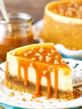 A slice of Salted Caramel Cheesecake next to a fork on a white plate