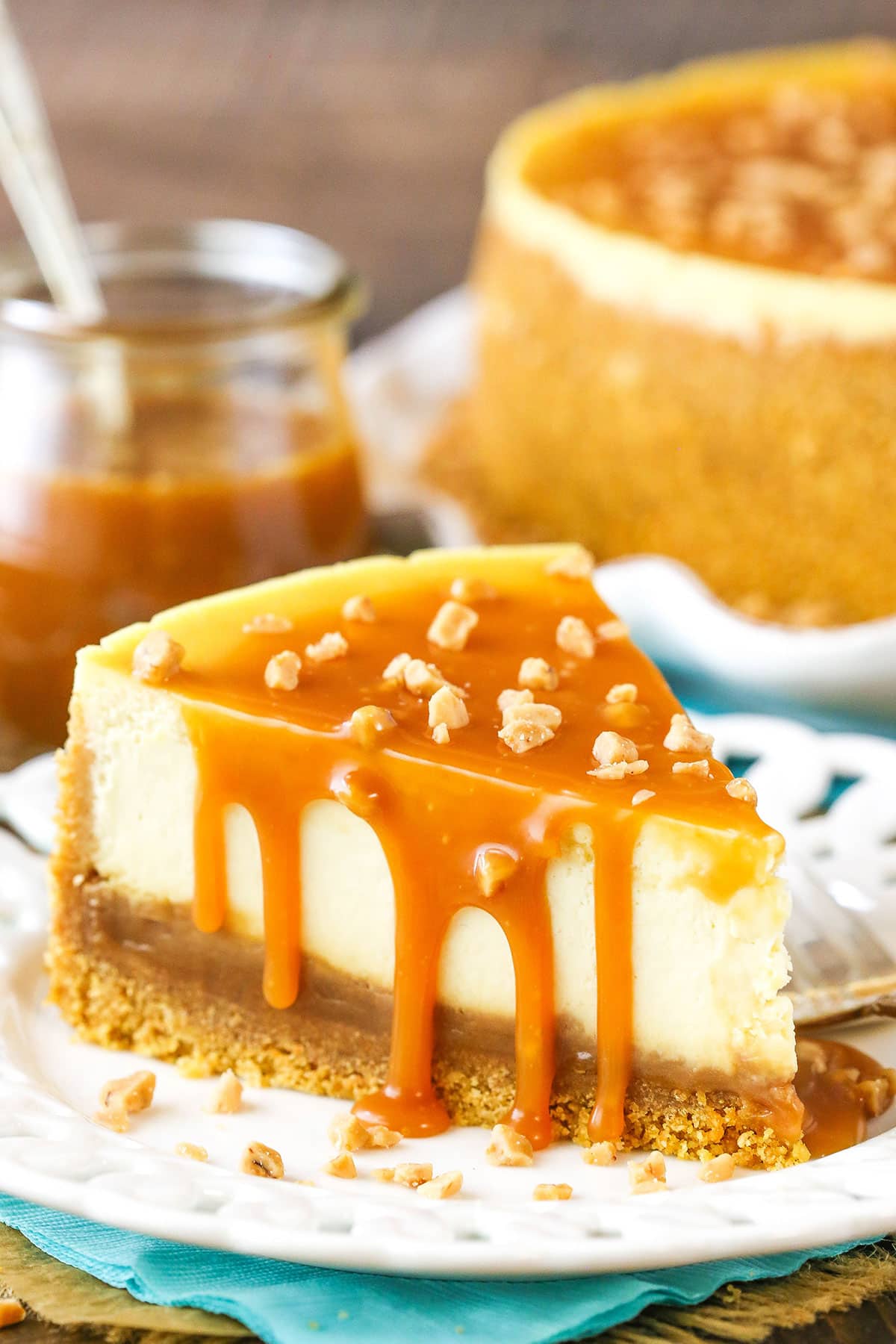 A slice of Salted Caramel Cheesecake next to a fork on a white plate