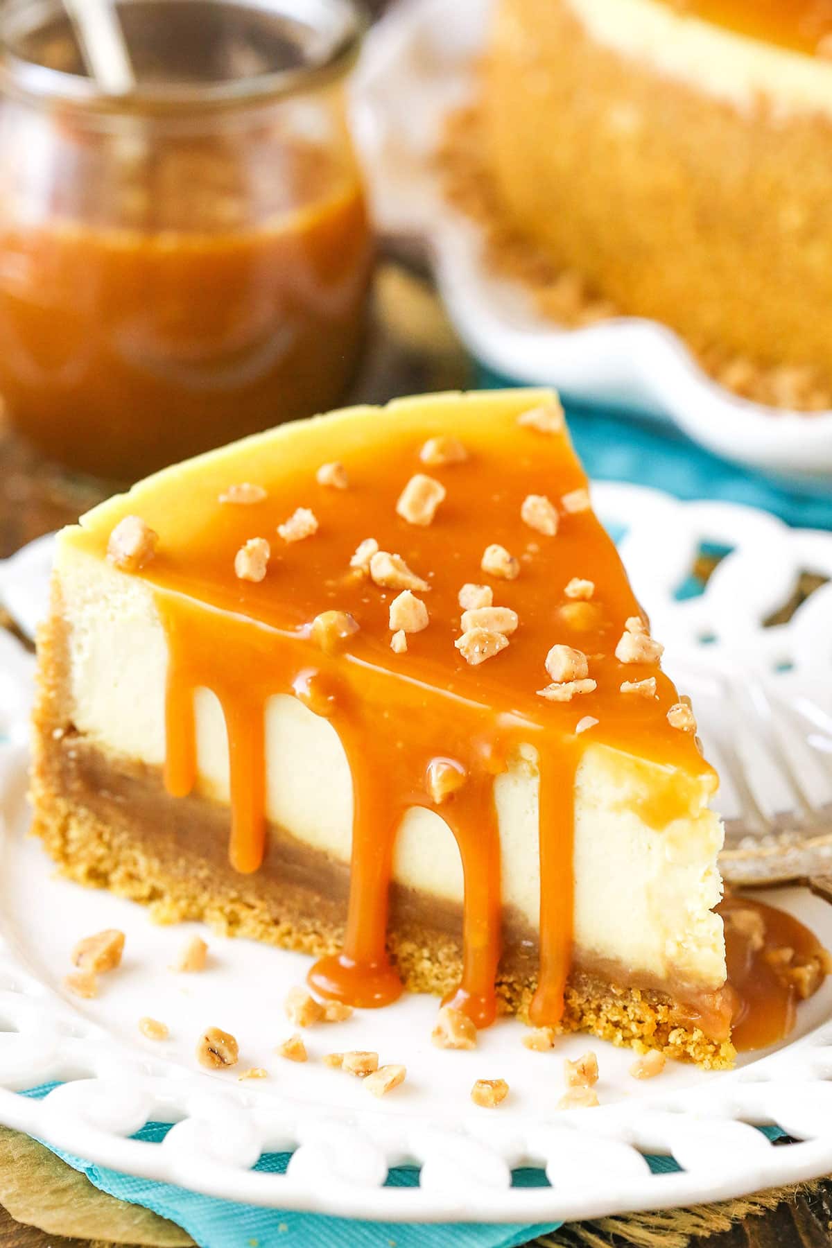 A slice of Salted Caramel Cheesecake next to a fork on a white plate