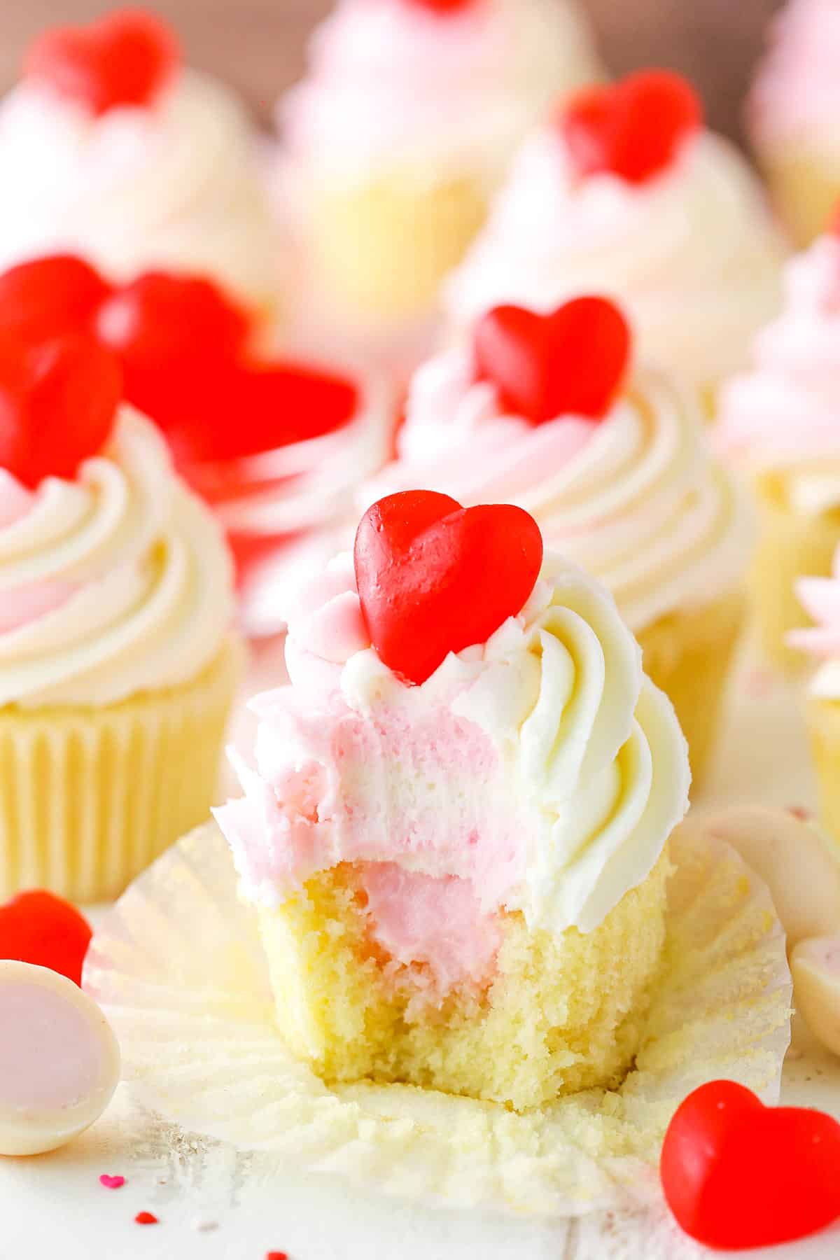 A Strawberry Truffle Cupcake with a bite taken out on a white table