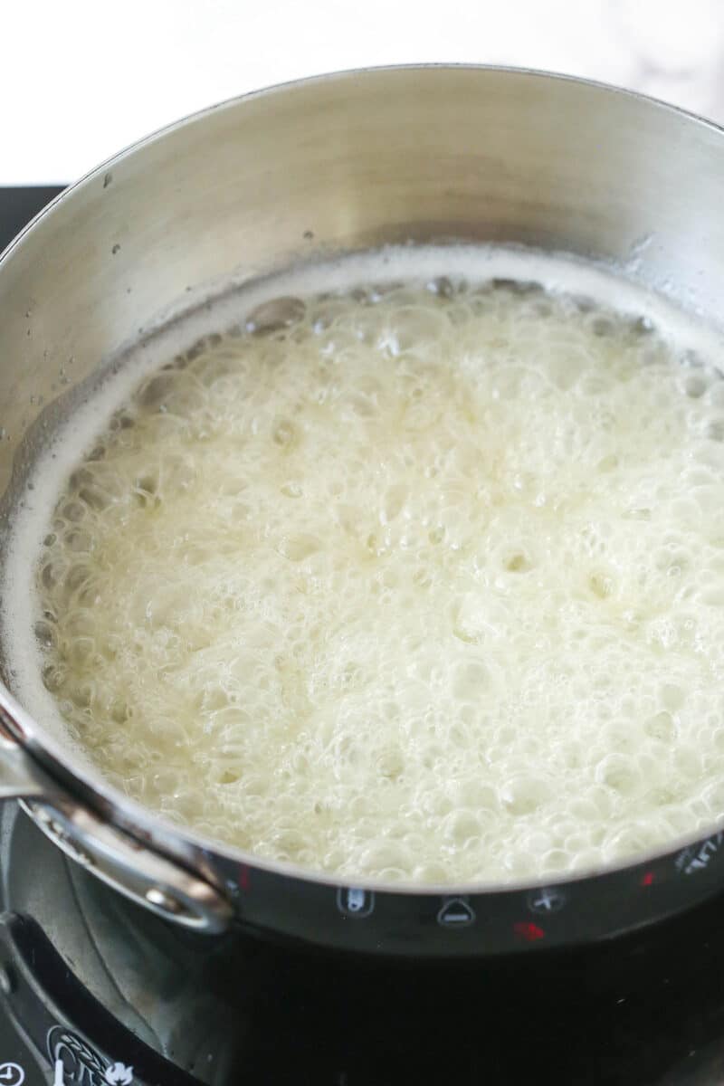 Sugar mixture in a metal pot boiling with slight change in color.