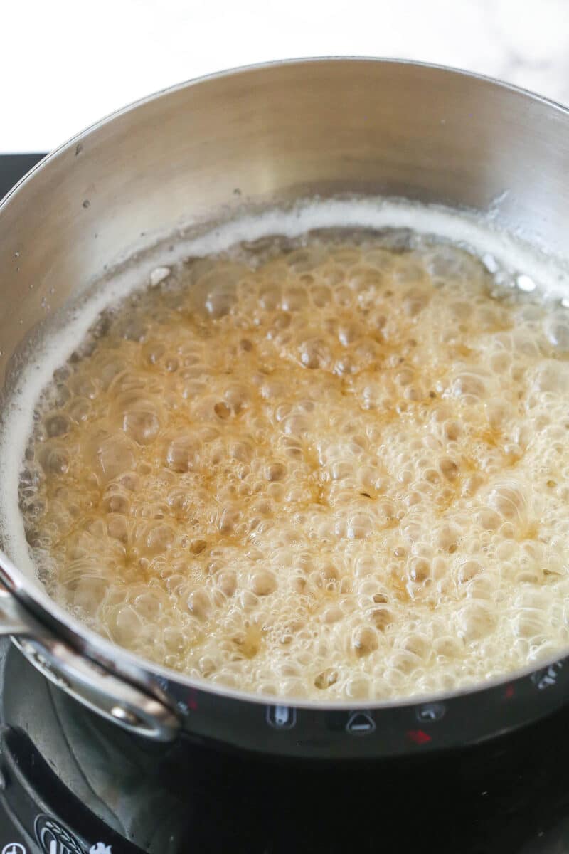 Sugar mixture in a metal pot boiling with deep copper color.