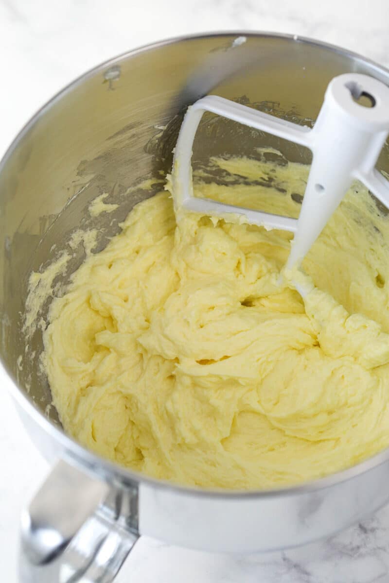 Adding eggs to creamed butter, oil, sugar, and vanilla to make cake batter.