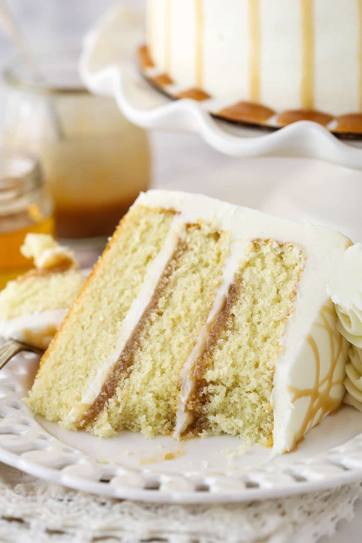 A slice of vanilla bourbon cake with a bite taken out of it on a plate.