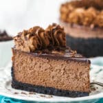 A slice of chocolate cheesecake with Oreo crust on a plate.