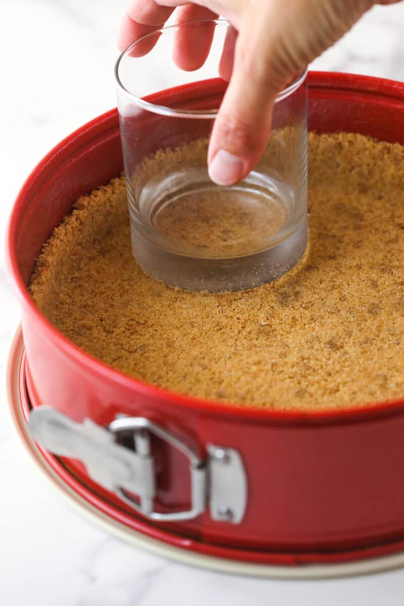 Pressing cinnamon crust into the bottom of a springform pan.