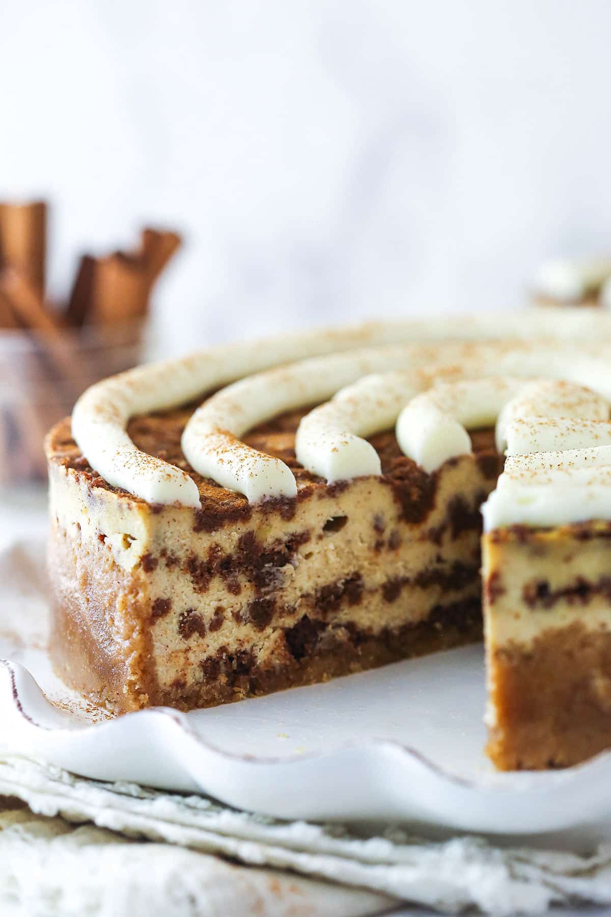 Cinnamon roll cheesecake with a slice taken out of it.