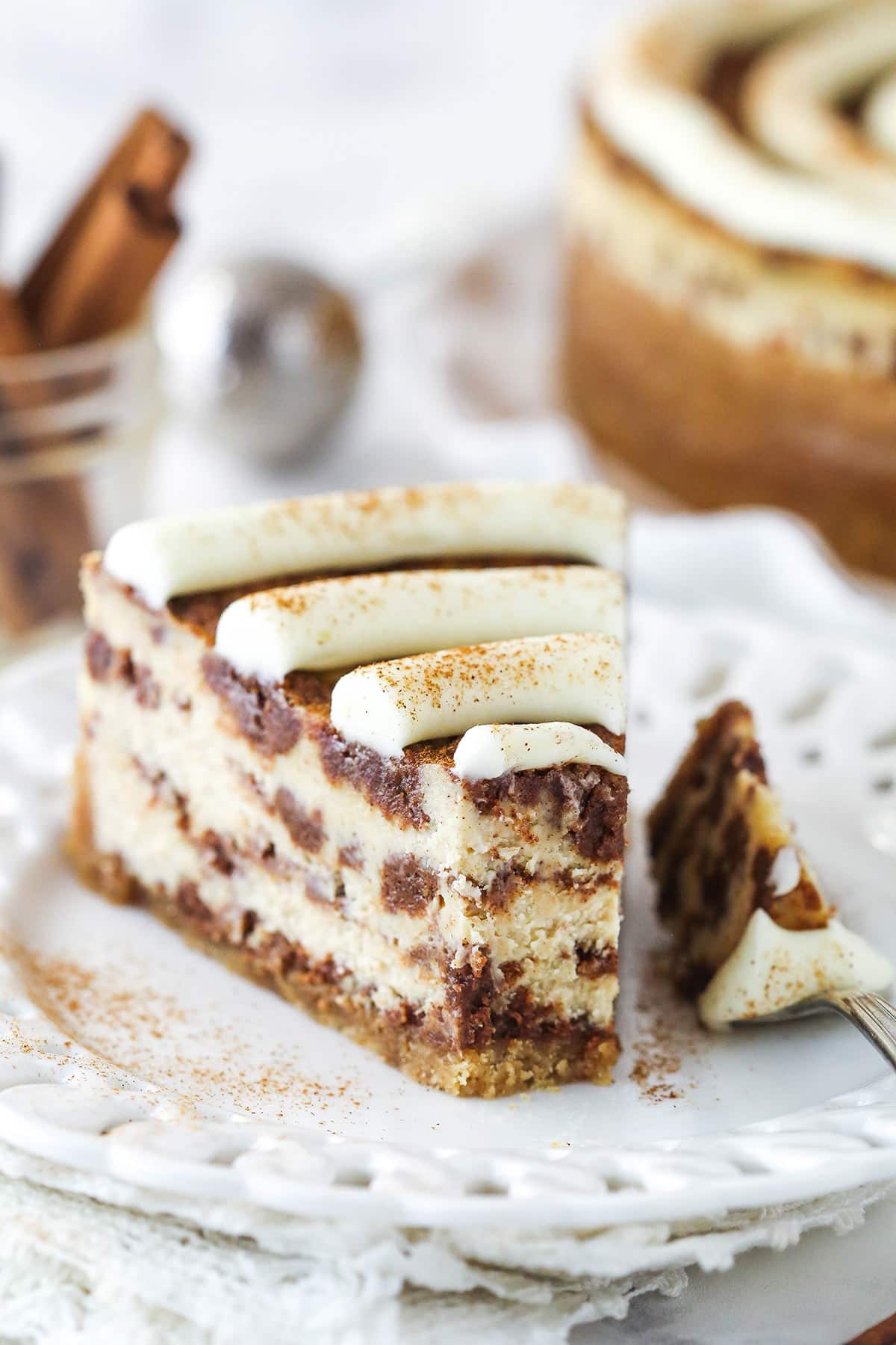 A slice of cinnamon roll cheesecake with a bite taken out of it.