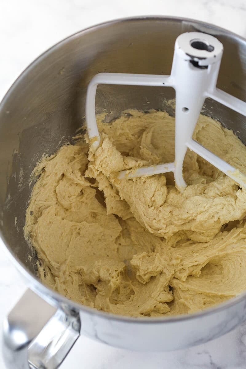 Overhead view of a silver mixing bowl of creamed ingredients after adding the egg, applesauce, and vanilla.