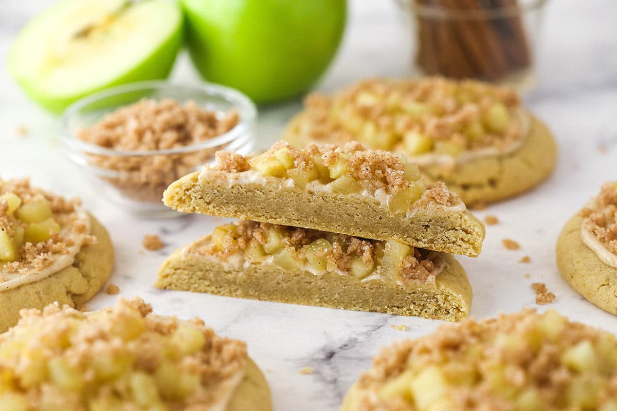 Close up of an apple crumb cake cookie that is cut in half and surrounded by more cookies.