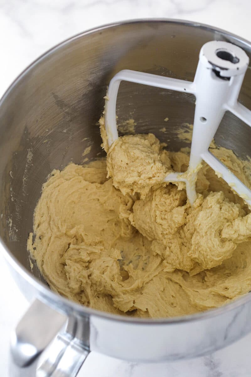 Adding eggs and vanilla to creamed butter and sugars to make cookie dough.