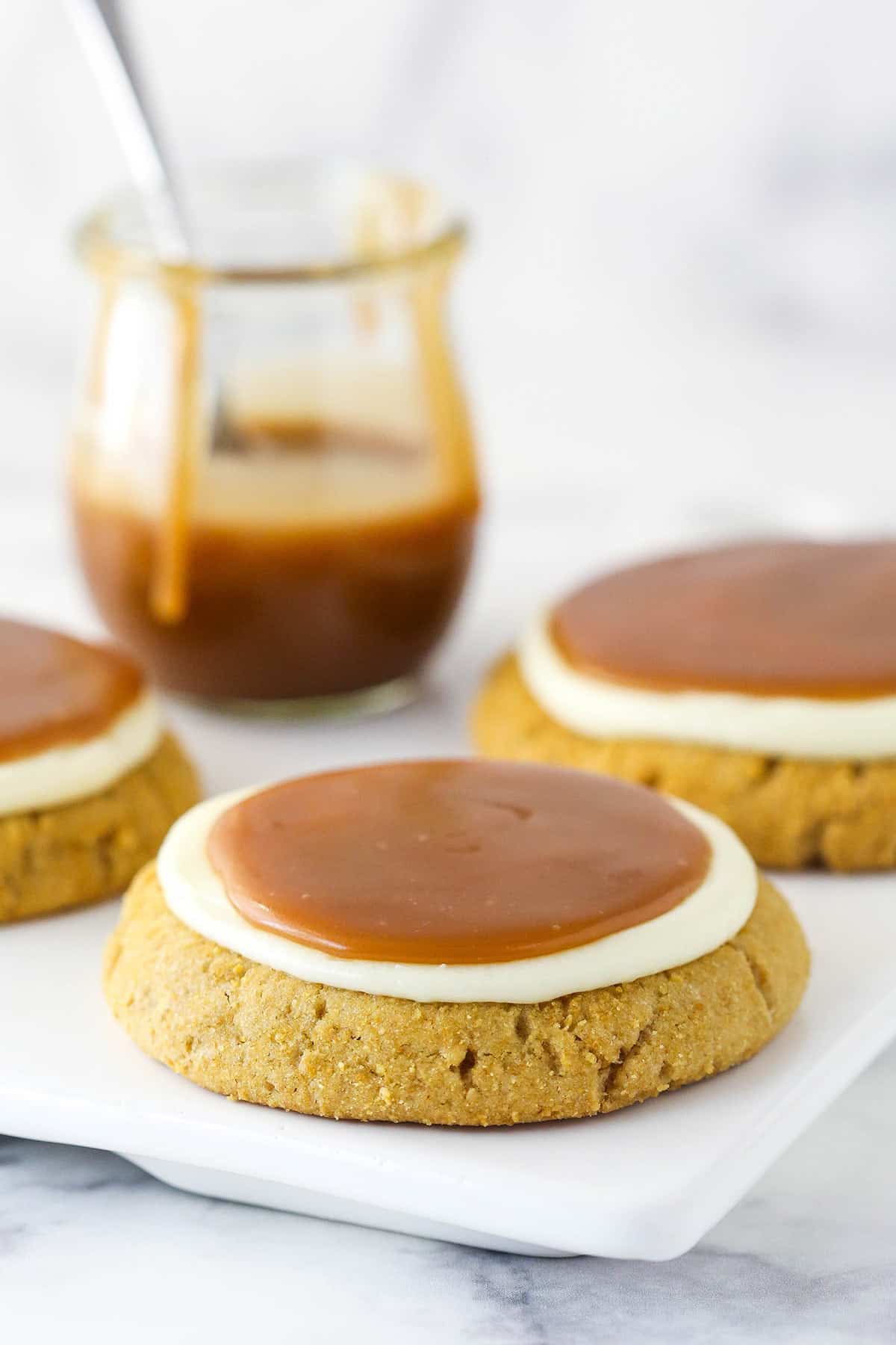Salted caramel cheesecake cookies are made of giant graham cracker cookies, tangy cheesecake topping, and luscious salted caramel sauce. Salted caramel cheesecake cookies ready to be eaten.