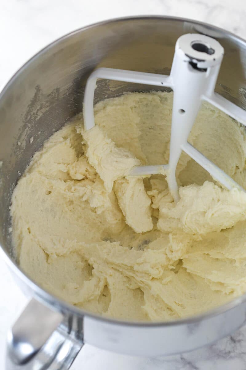 Close up of a mixing bowl with creamed butter and sugar in it for Halloween Monster Cookies.