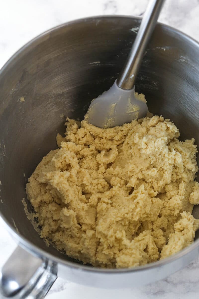 Close up of a mixing bowl with dry ingredients mixed into the batter for Halloween Monster Cookies.