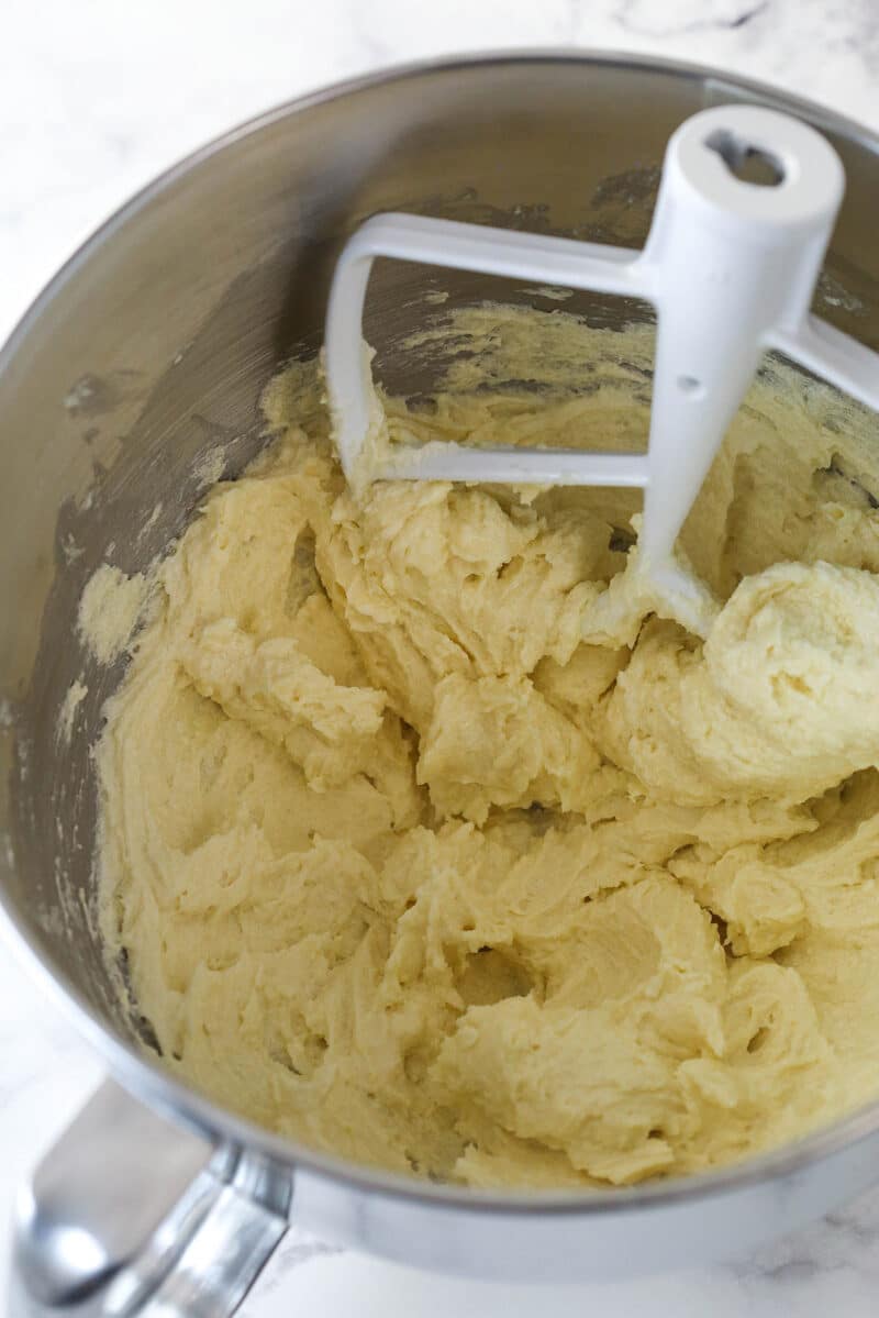 Close up of a mixing bowl with eggs and vanilla mixed into the batter for Halloween Monster Cookies.