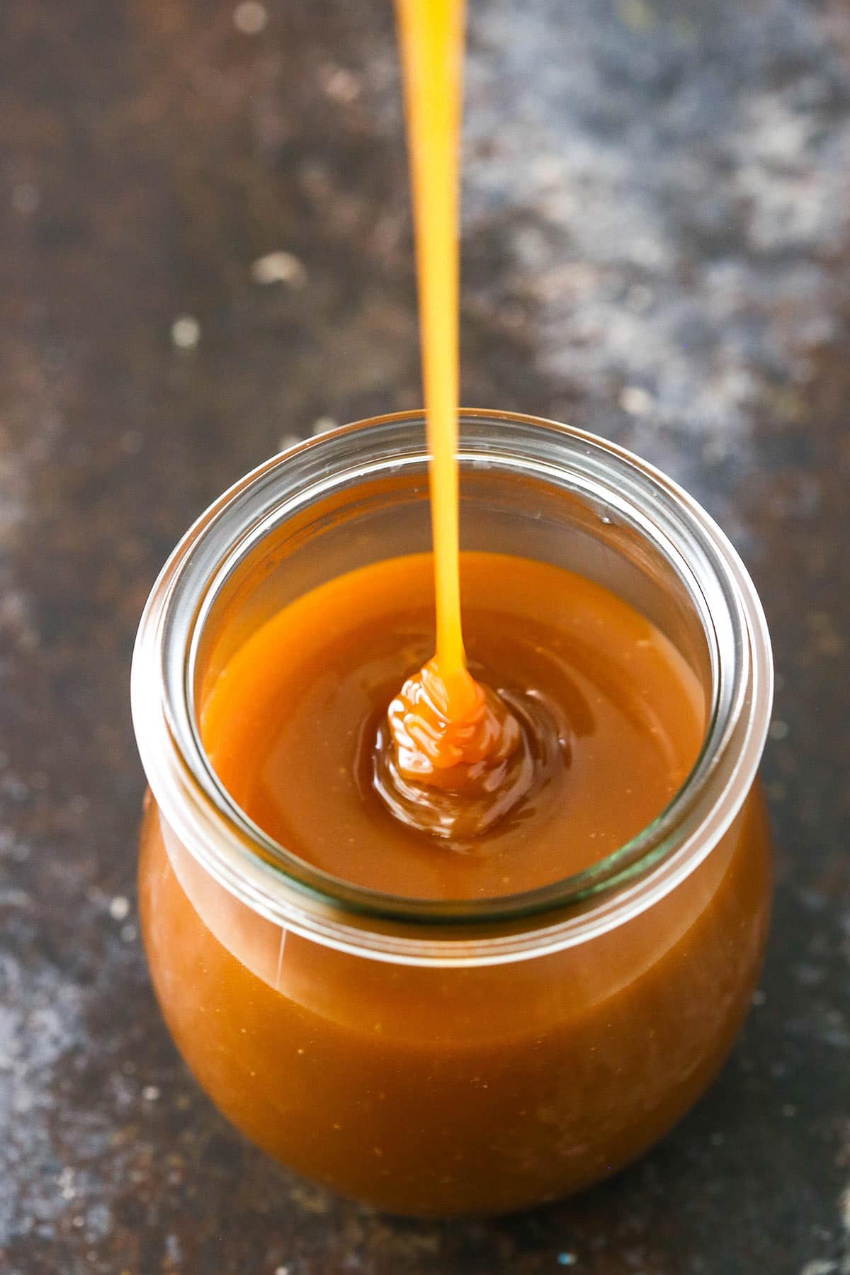 Overhead image of caramel sauce being drizzled into a jar.