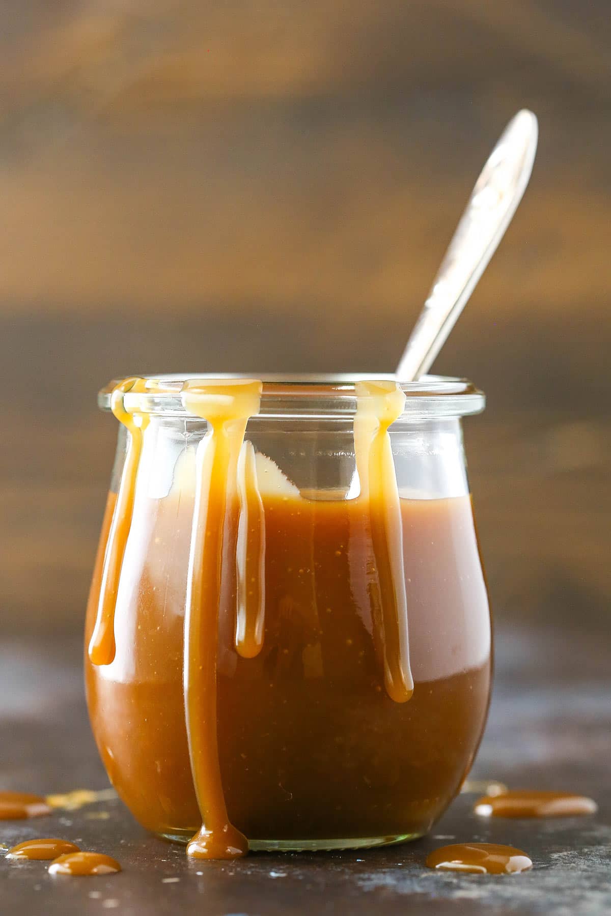 A jar of caramel sauce with a spoon on it.