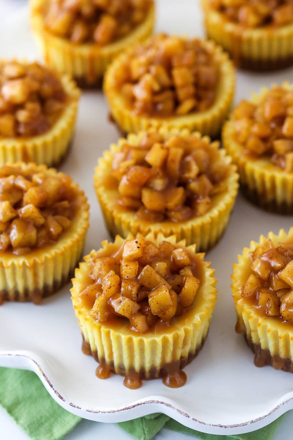 Overhead of mini caramel apple cheesecakes on a serving platter.