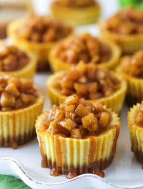 Mini caramel apple cheesecakes on a serving platter.