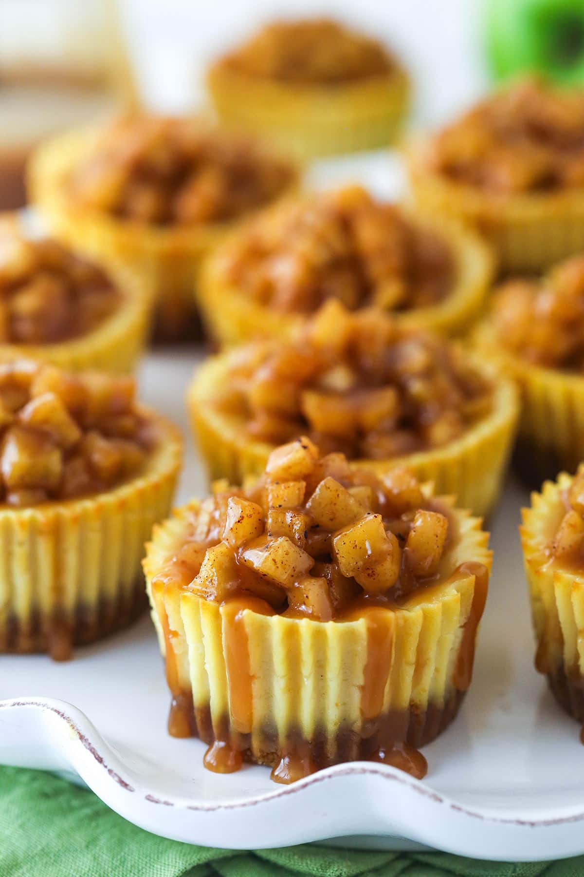 Mini caramel apple cheesecakes on a serving platter.