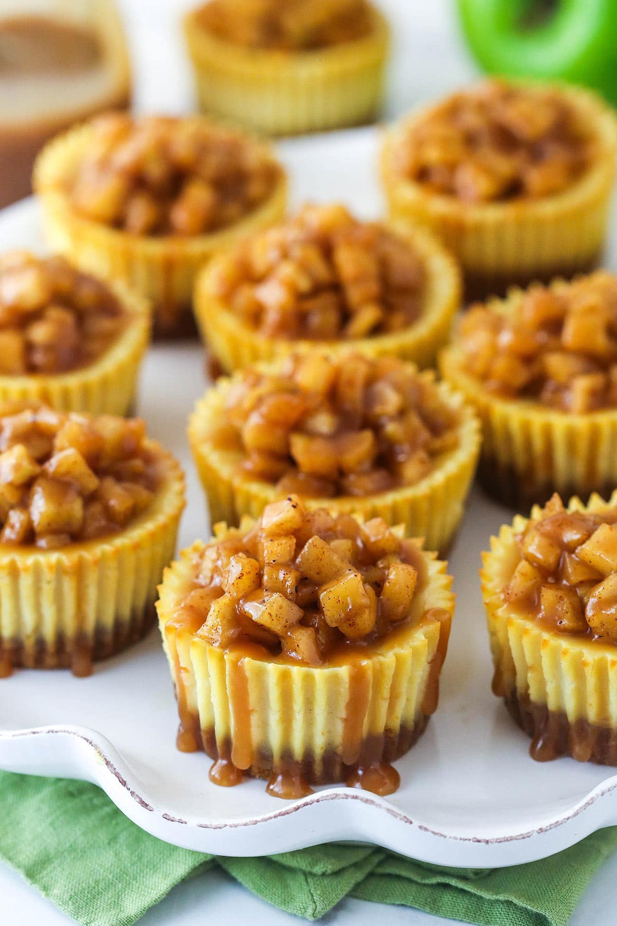 Mini caramel apple cheesecakes on a serving platter.