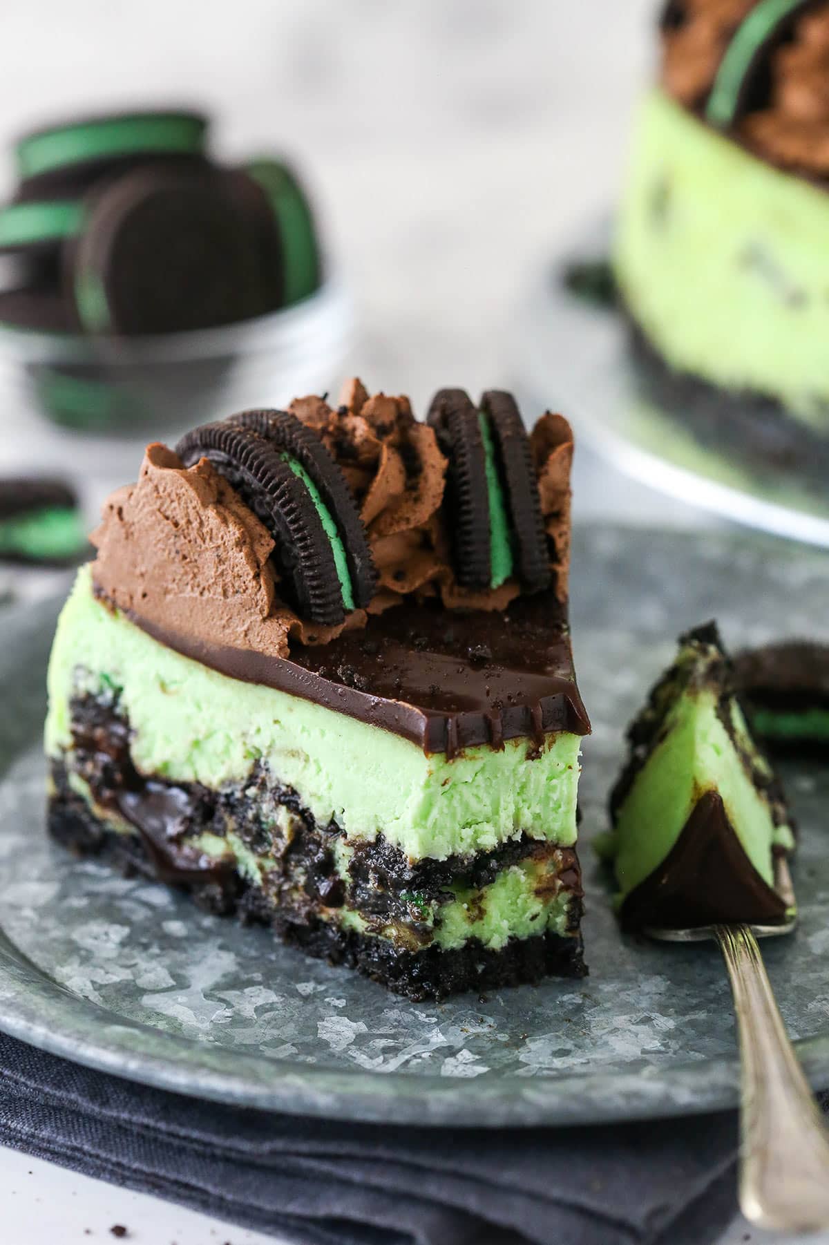 A slice of mint Oreo cheesecake with a bite taken out of it.