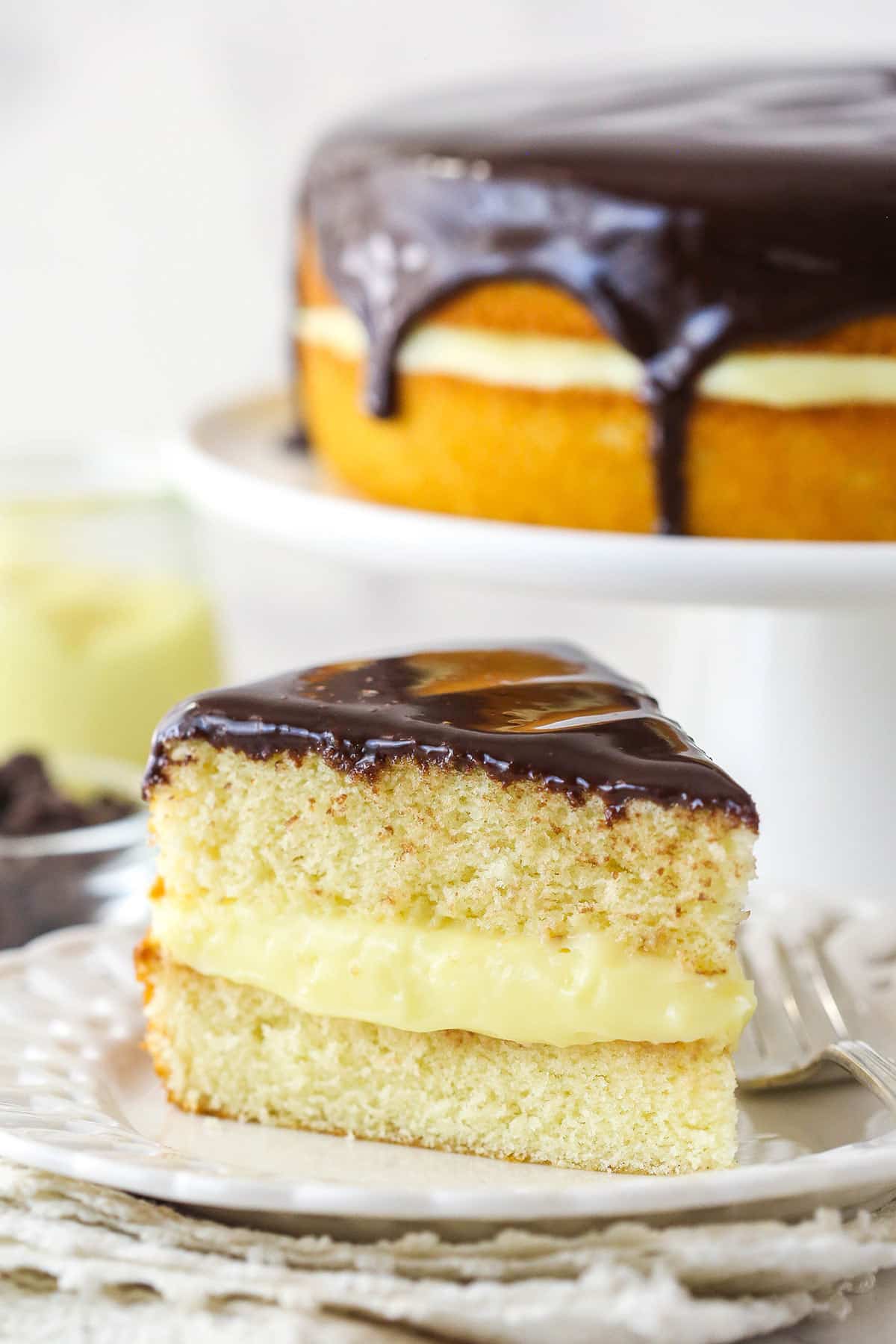 A slice of Boston cream pie on a plate with a fork.