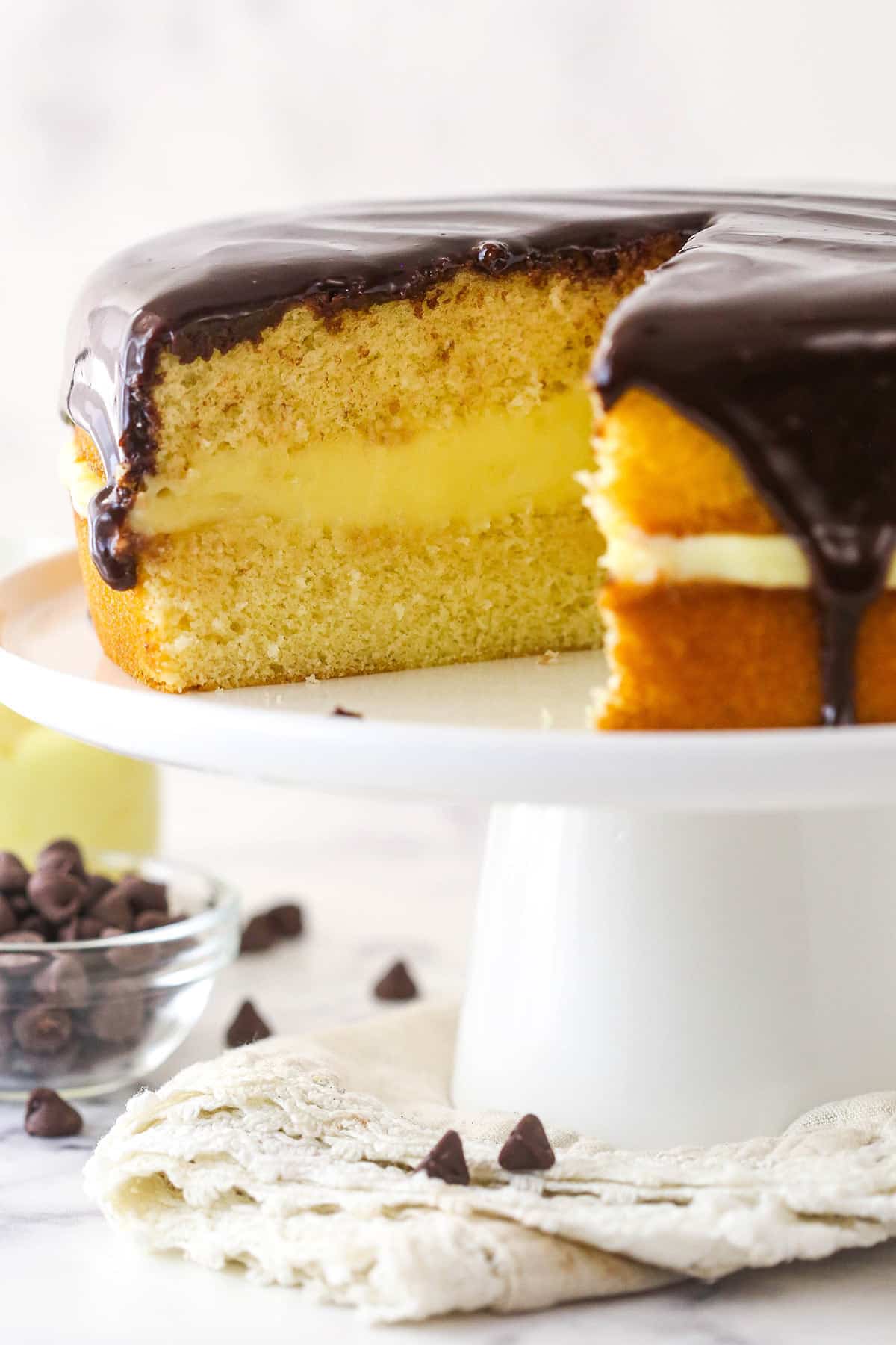 Boston cream pie on a cake stand with a slice taken out of it.