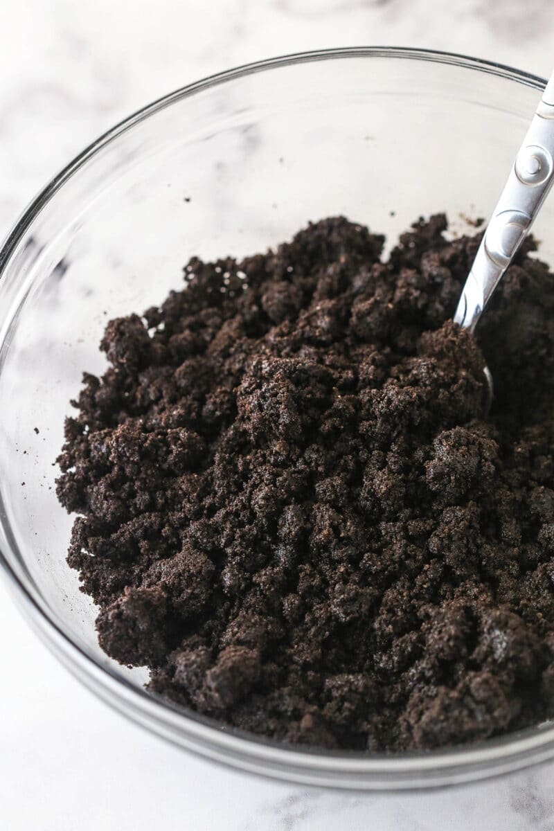 Combining Oreo crumbs and melted butter to make Oreo pie crust.