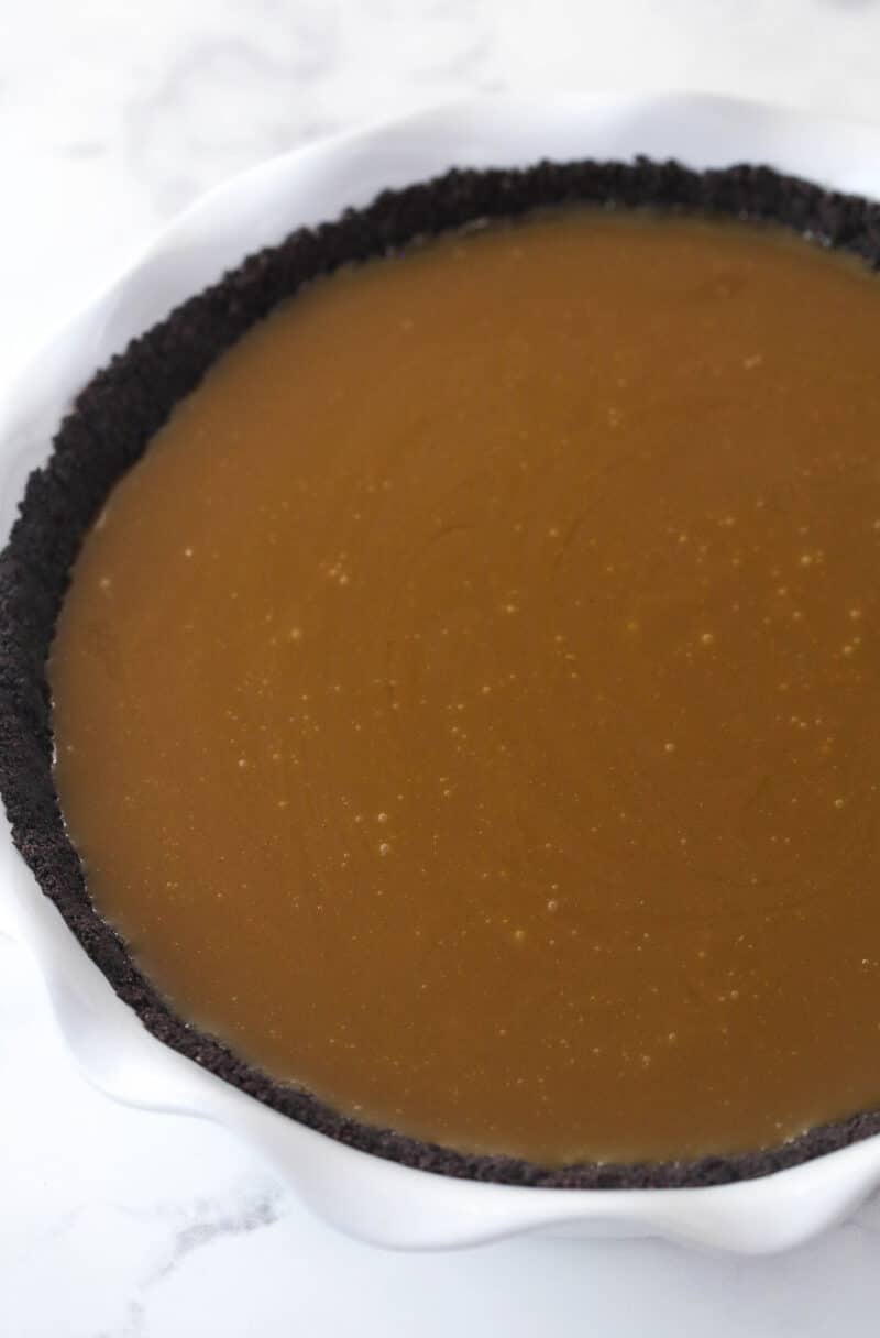 Filling an Oreo pie crust with caramel filling.