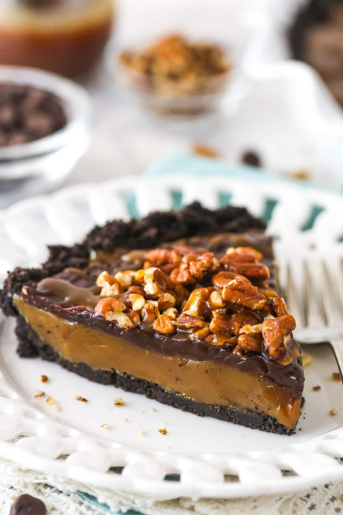 This easy no-bake caramel turtle pie features a buttery chocolate crust, a gooey caramel filling, rich chocolate ganache, and crunchy pecans. A slice of caramel turtle pie on a plate.