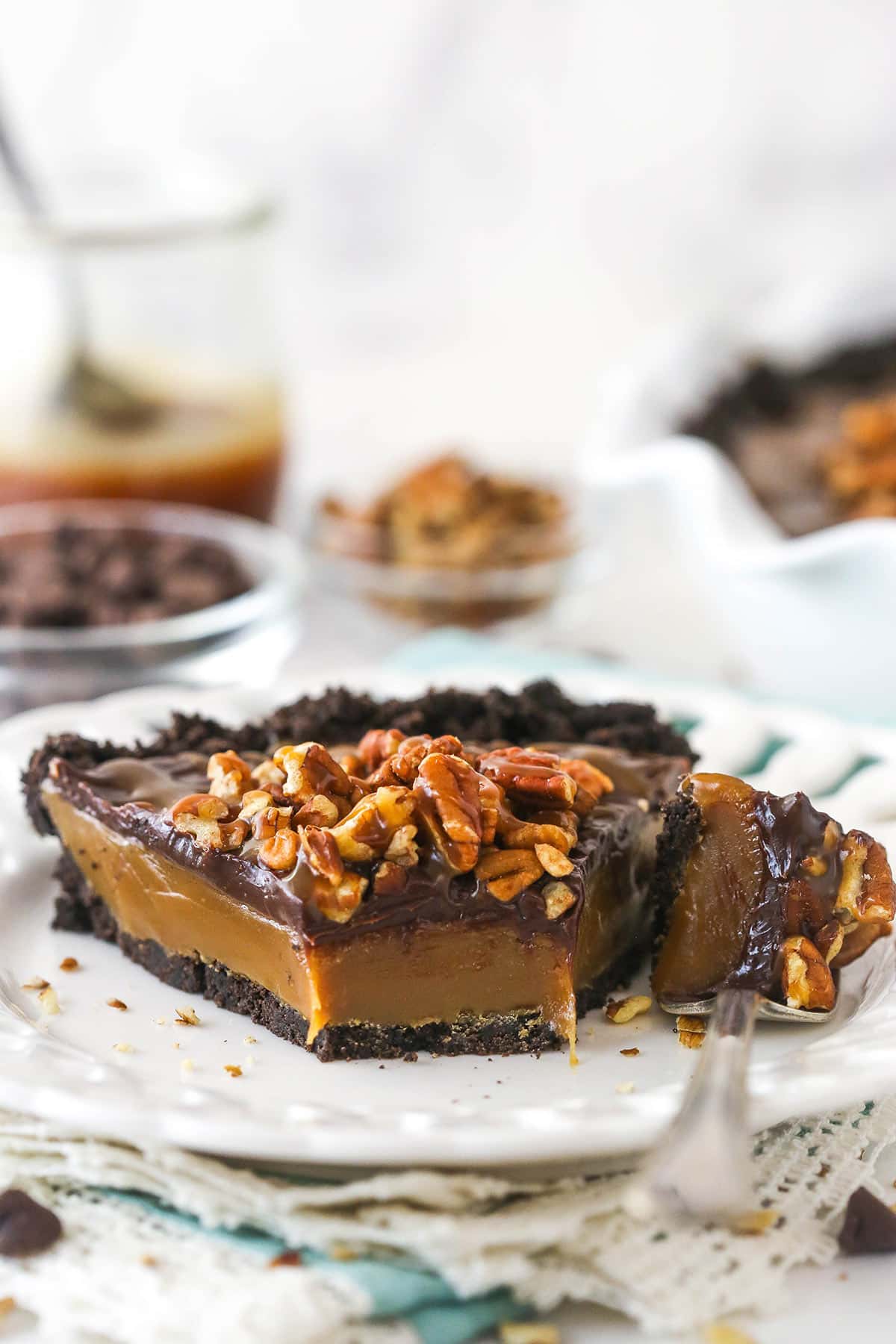 A slice of caramel turtle pie on a plate with a fork taking a bite out of it.