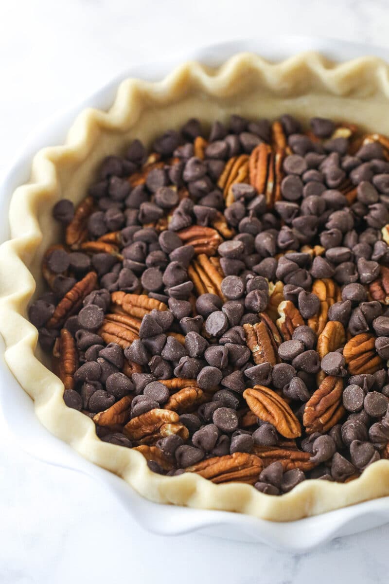 Chocolate chips and pecans in an unbaked pie crust.