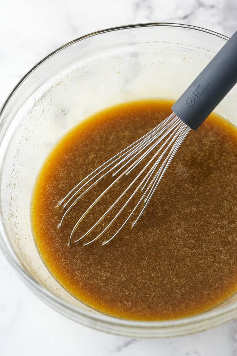 Whisking together eggs, dark corn syrup, dark brown sugar, vanilla, butter, and salt for chocolate pecan pie filling.