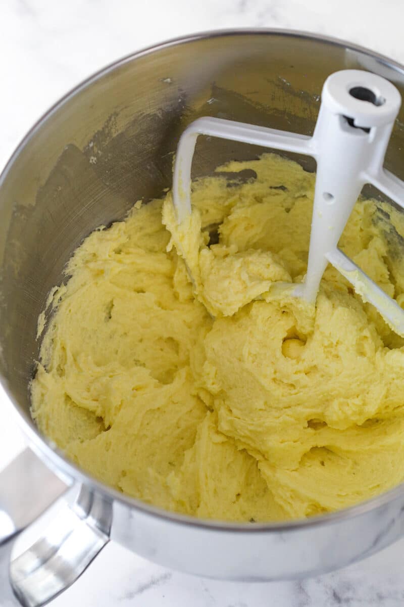 Adding egg yolks, vanilla, and sour cream to cake batter.