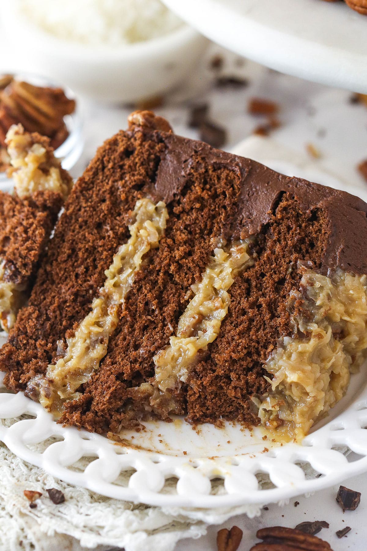 A slice of German chocolate cake on a plate with a bite taken out of it.