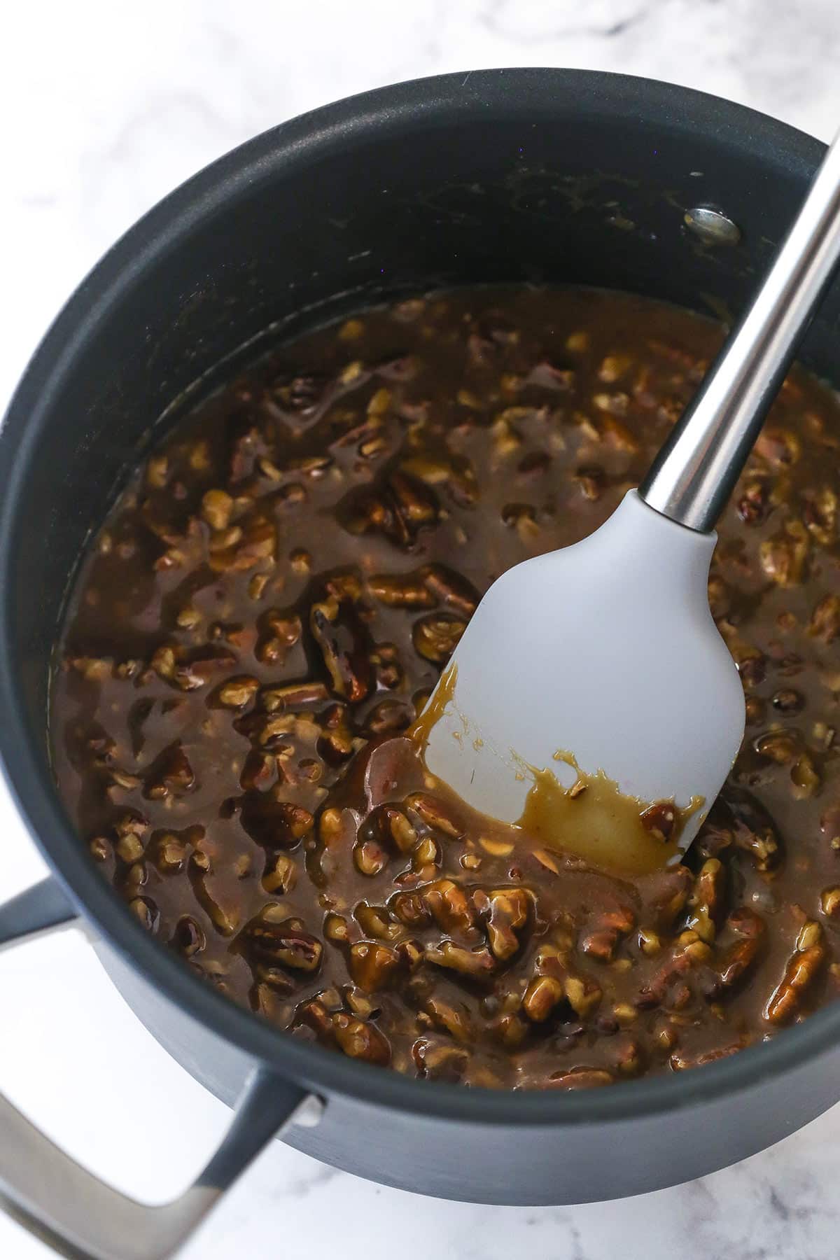 Stirring pecan topping in a saucepan.