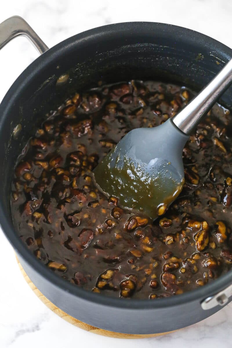 Stirring pecan pie filling in a saucepan.