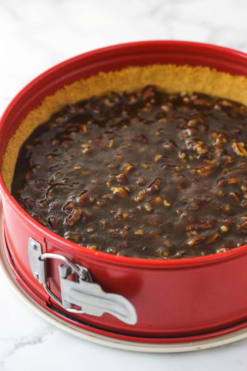 Pecan pie filling in a graham cracker crust in a springform pan.