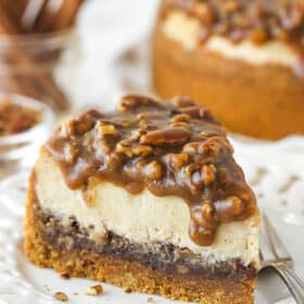 A slice of pecan pie cheesecake eon a plate with a fork.
